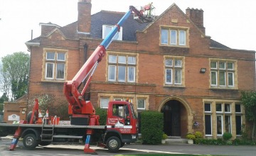 An elevated access platform reaching the roofline of a large period building for high-level gutter cleaning