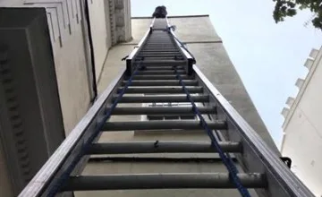 Ladder set up against a property wall ready for hand-cleaning the gutters